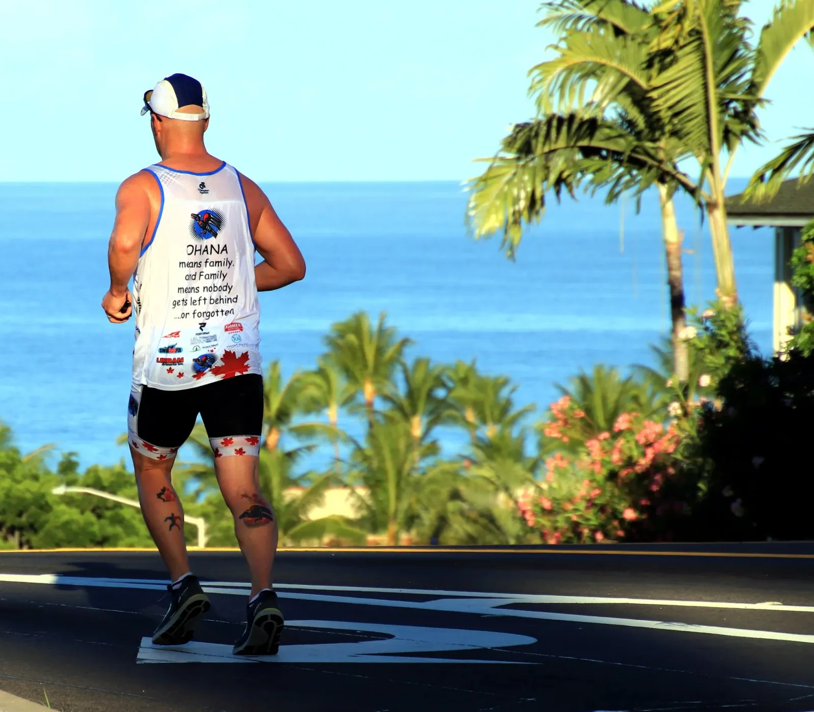 Runner on a road with a scenic waterfront and palm trees in the background.