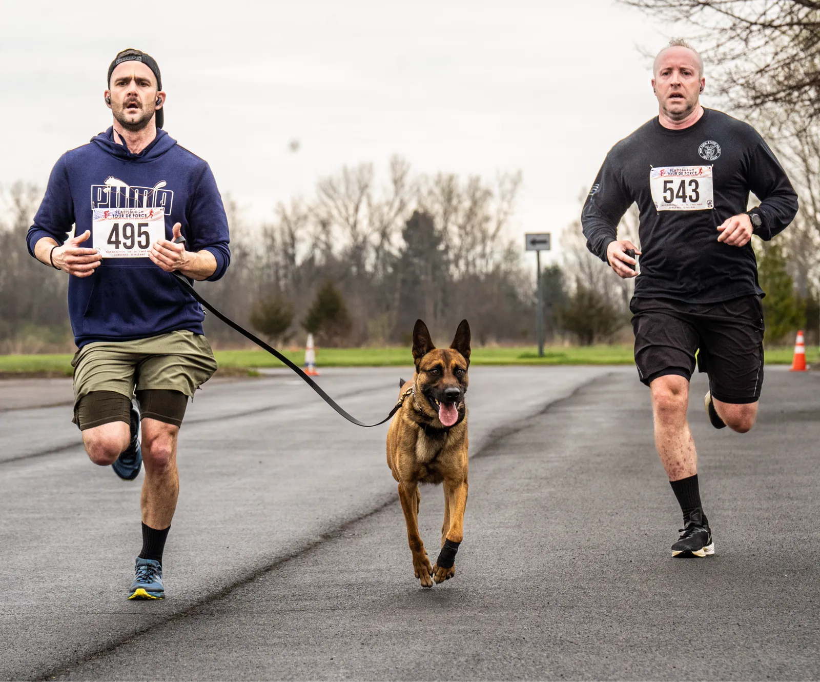 Two runners participating in the Plattsburgh Tour de Force Charity Run, with one runner accompanied by a dog.