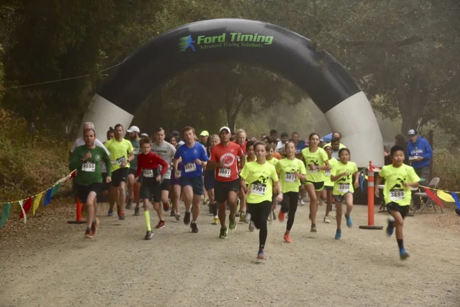 Runners start the Lake Chabot Trail Challenge Half Marathon under a Ford Timing arch.