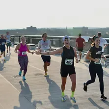 Runners smiling and running across a bridge during the Dutchess County Classic Half Marathon.