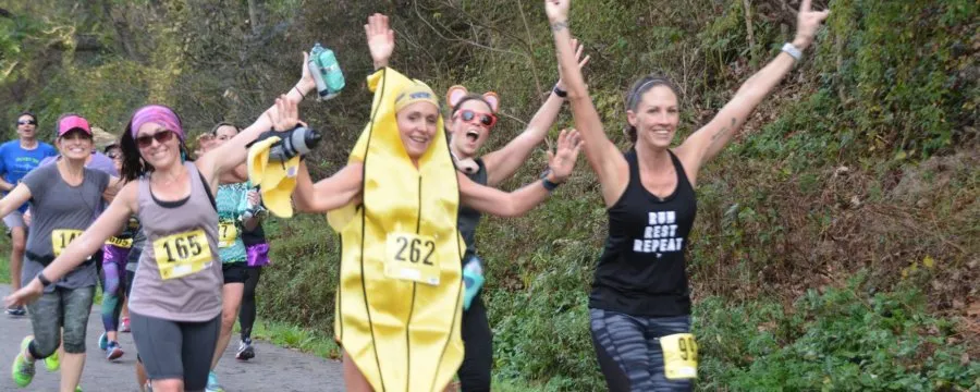 Runners celebrating during a race, one in a banana costume, with arms raised in excitement.