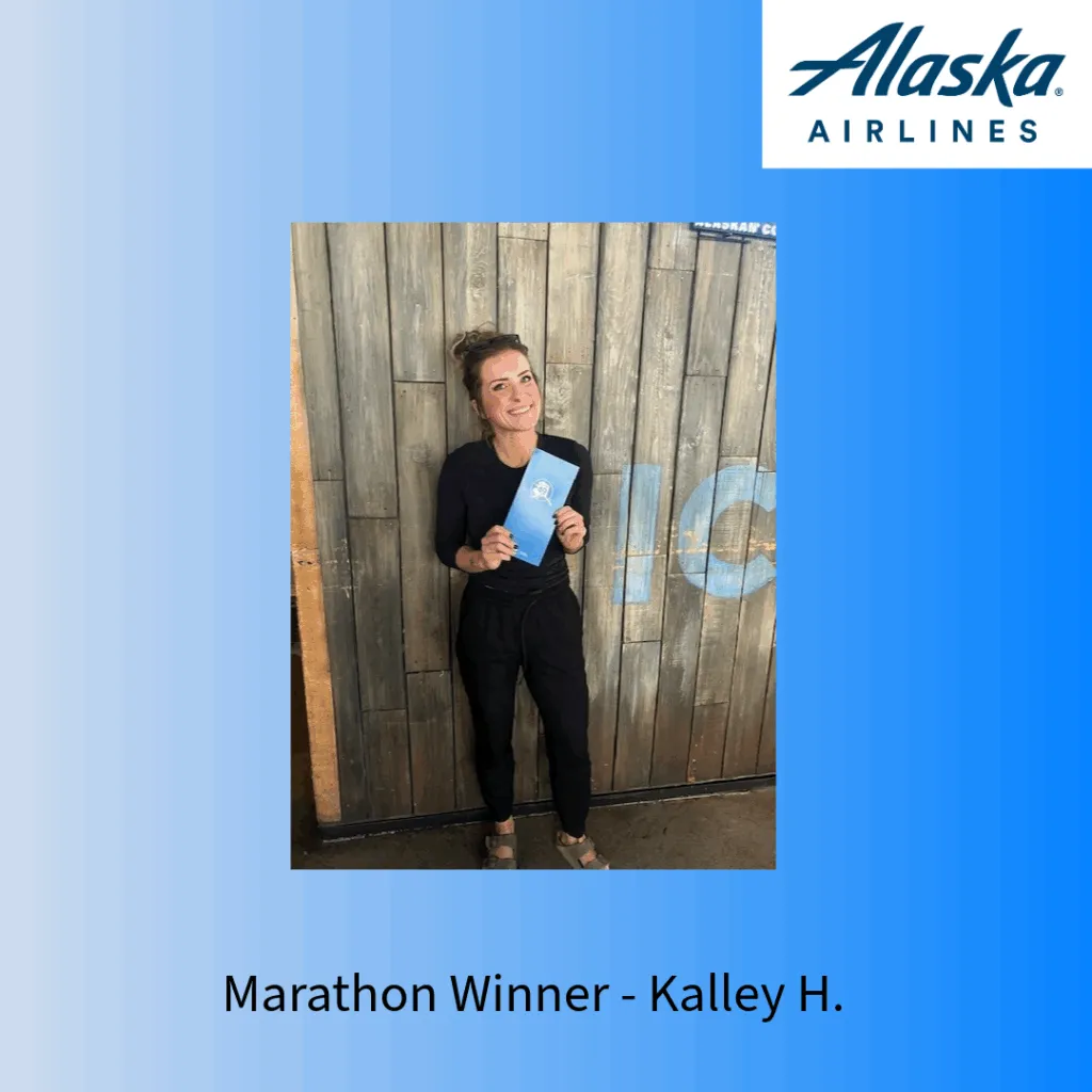 Marathon winner Kalley H. holding a blue folder in front of a wooden wall.