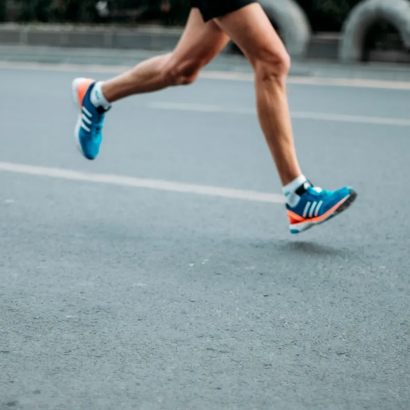 Close-up of a runner's legs and feet as they run on a road.