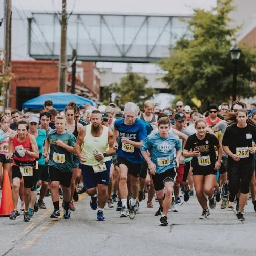 A large group of runners starting a race, with determined expressions on their faces.