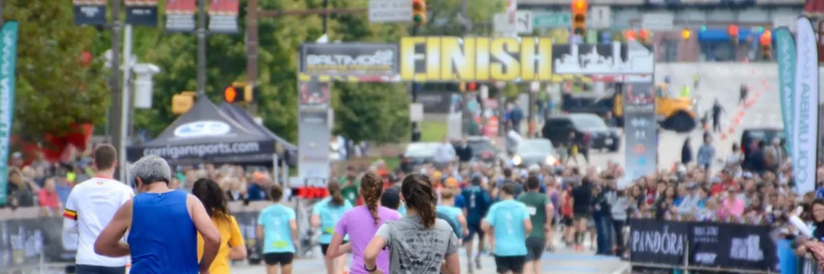 Runners approaching the finish line at the Baltimore Running Festival, with a large crowd cheering them on.