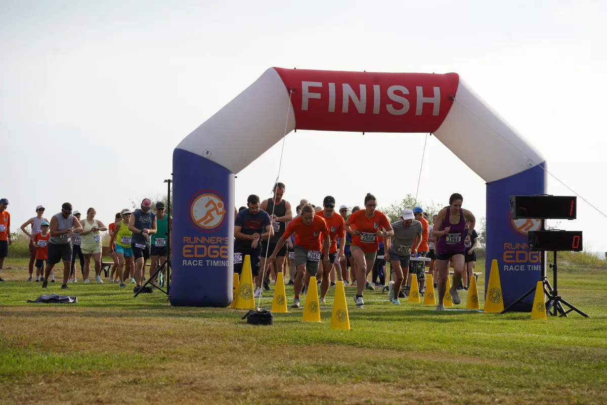 Runners gather at the start line under a large inflatable arch with 'FINISH' printed on it, ready for the race to begin.