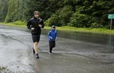 Two runners on a wet road with trees in the background.