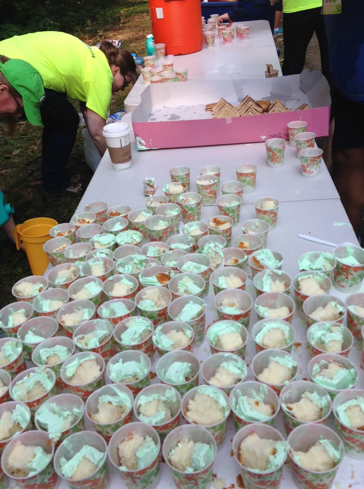 Volunteers at a race aid station serving cake to runners.