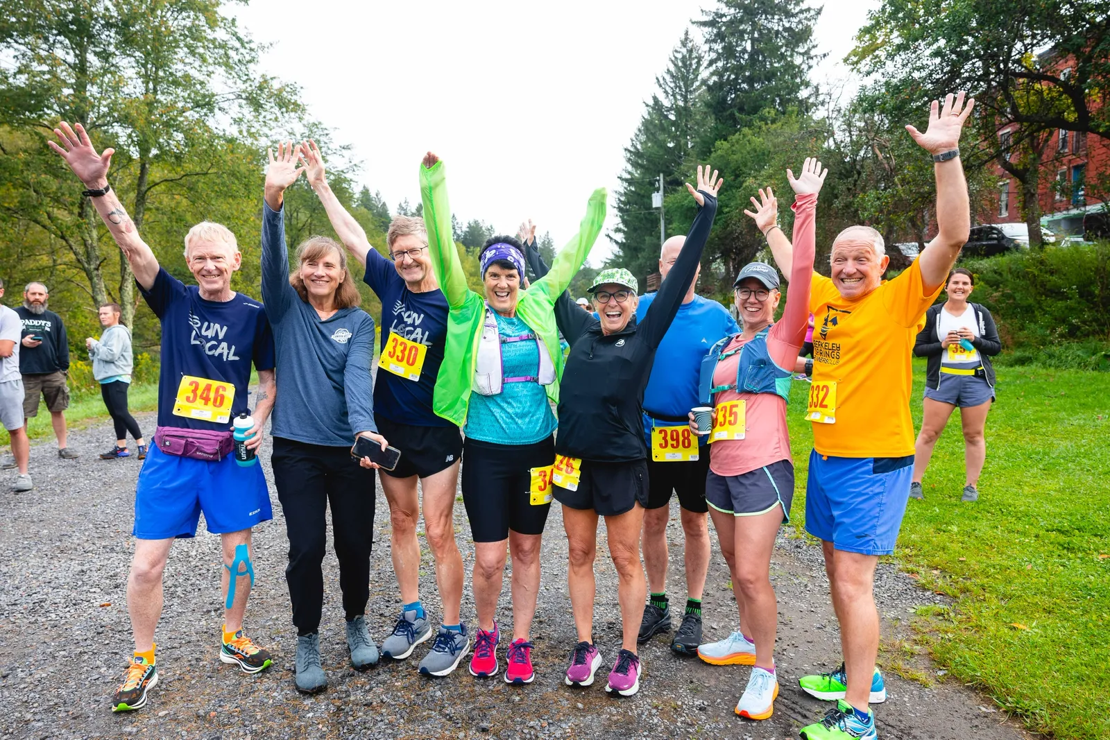 A group of runners with their arms raised in celebration, smiling at the camera.