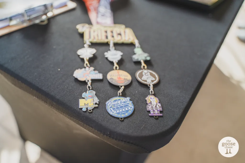 A collection of race medals with various charms, including one labeled 'Bluegrass Half Marathon'.