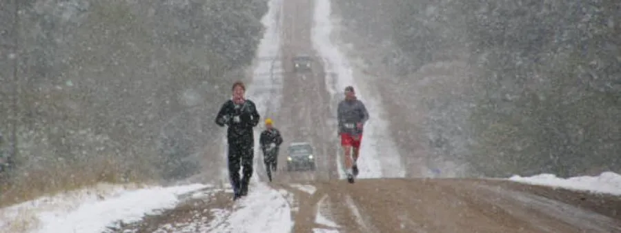 Runners navigate a snowy road during a race.