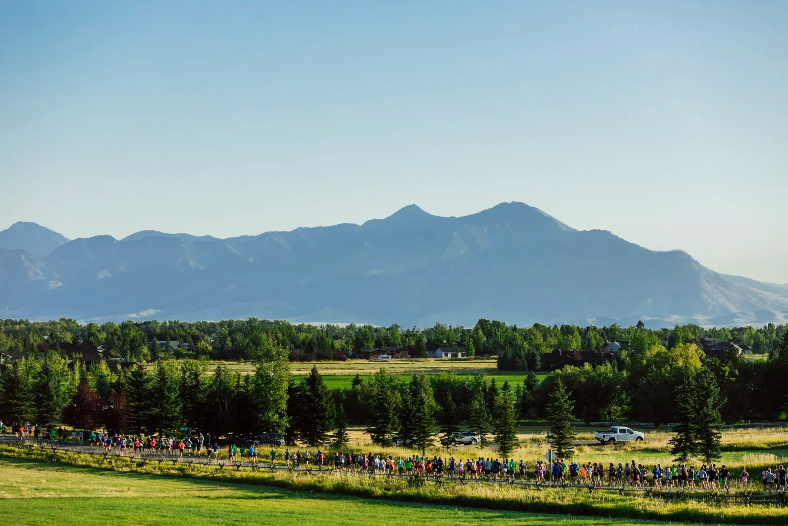 A group of runners on a road with a scenic mountain range in the background.