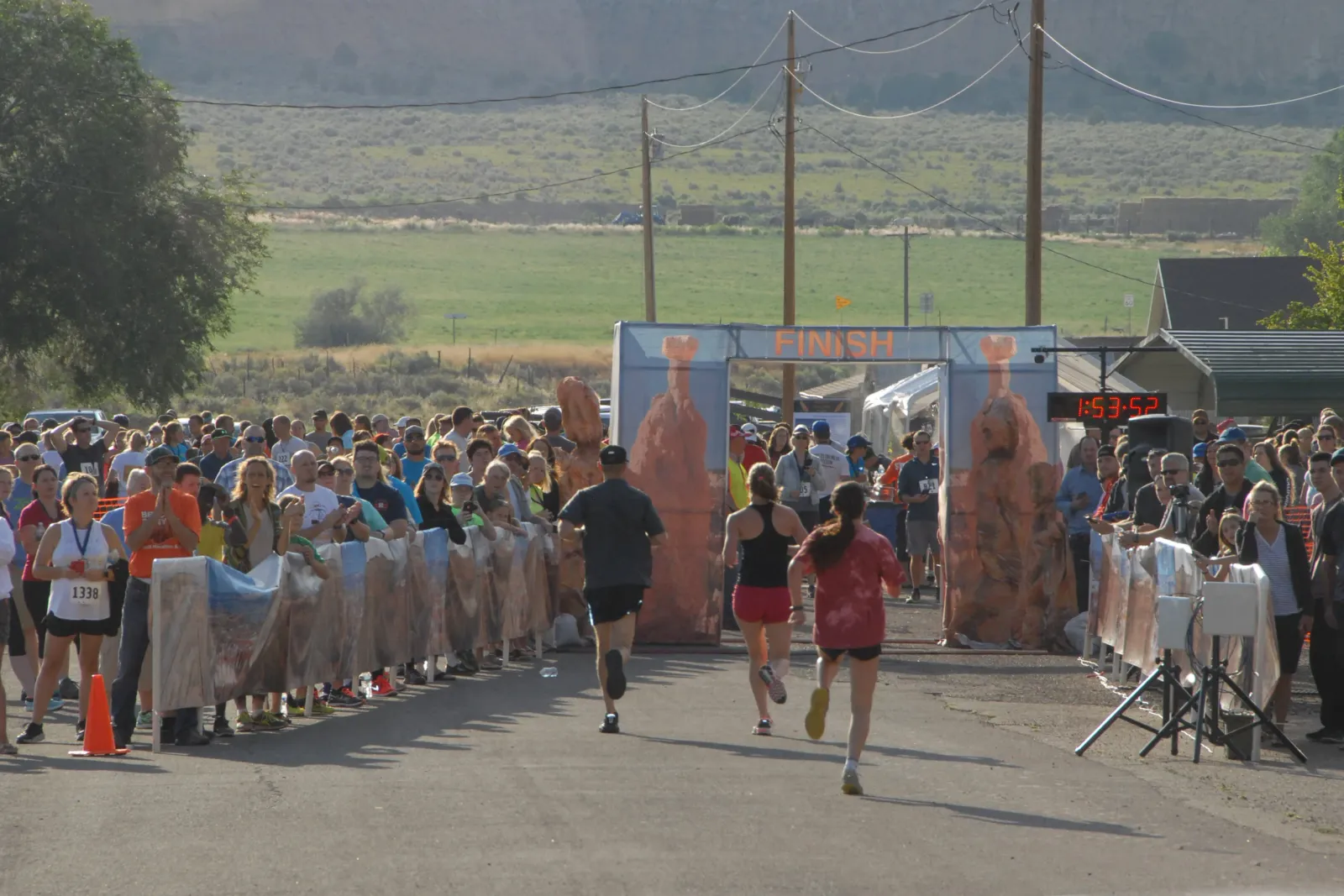 Runners crossing the finish line at a race, with spectators cheering them on.