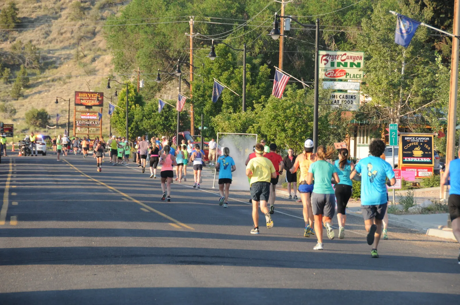 Runners on a road during the Bryce Canyon Half Marathon, with trees and buildings in the background.