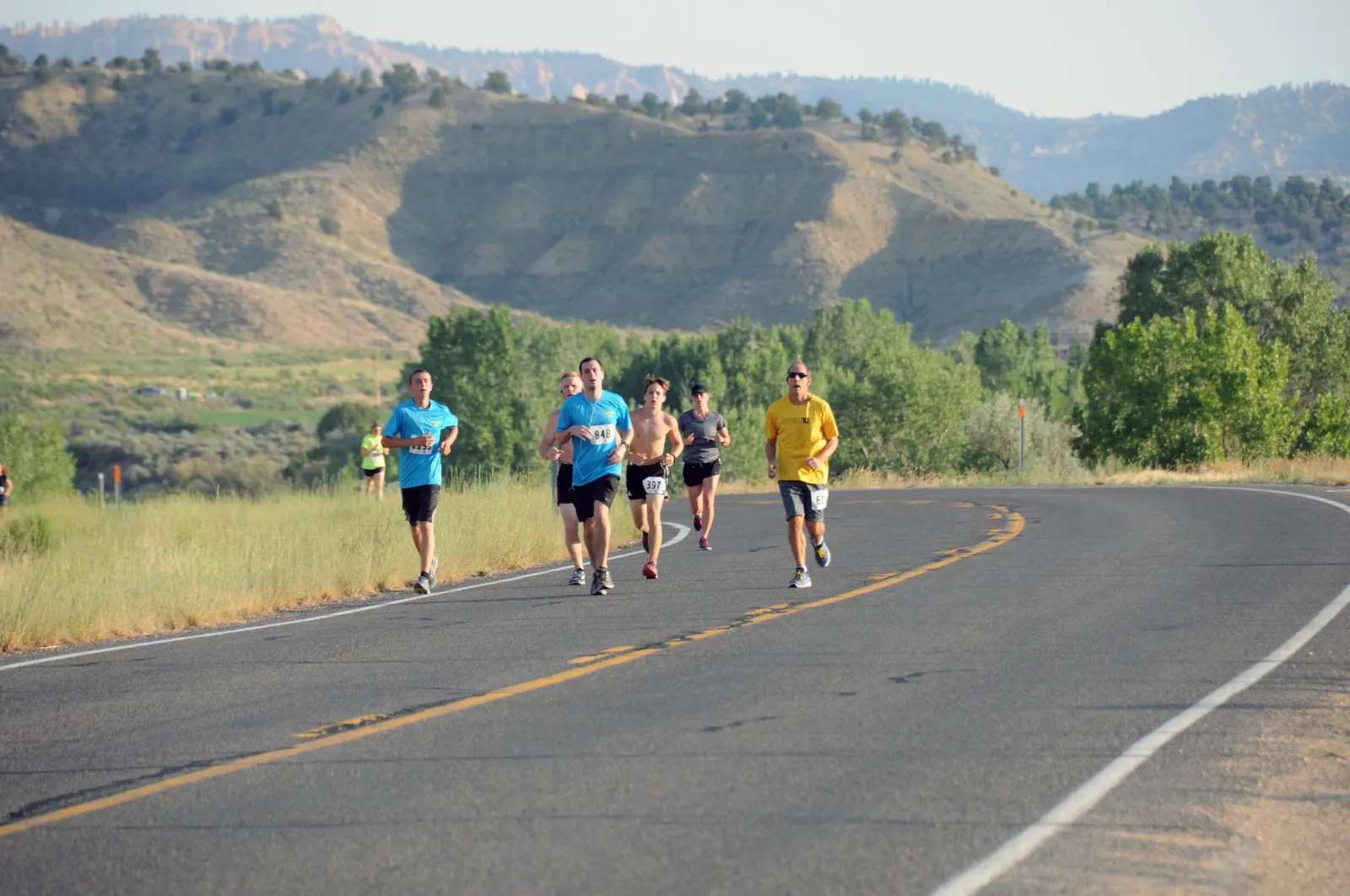 Runners on a road with scenic mountains in the background during a race.