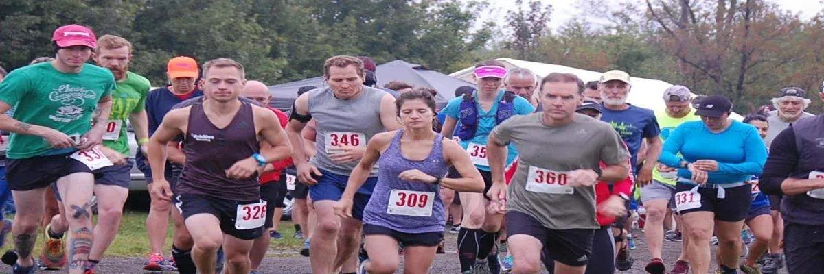 A group of runners in a race, with bib numbers visible, starting the run.