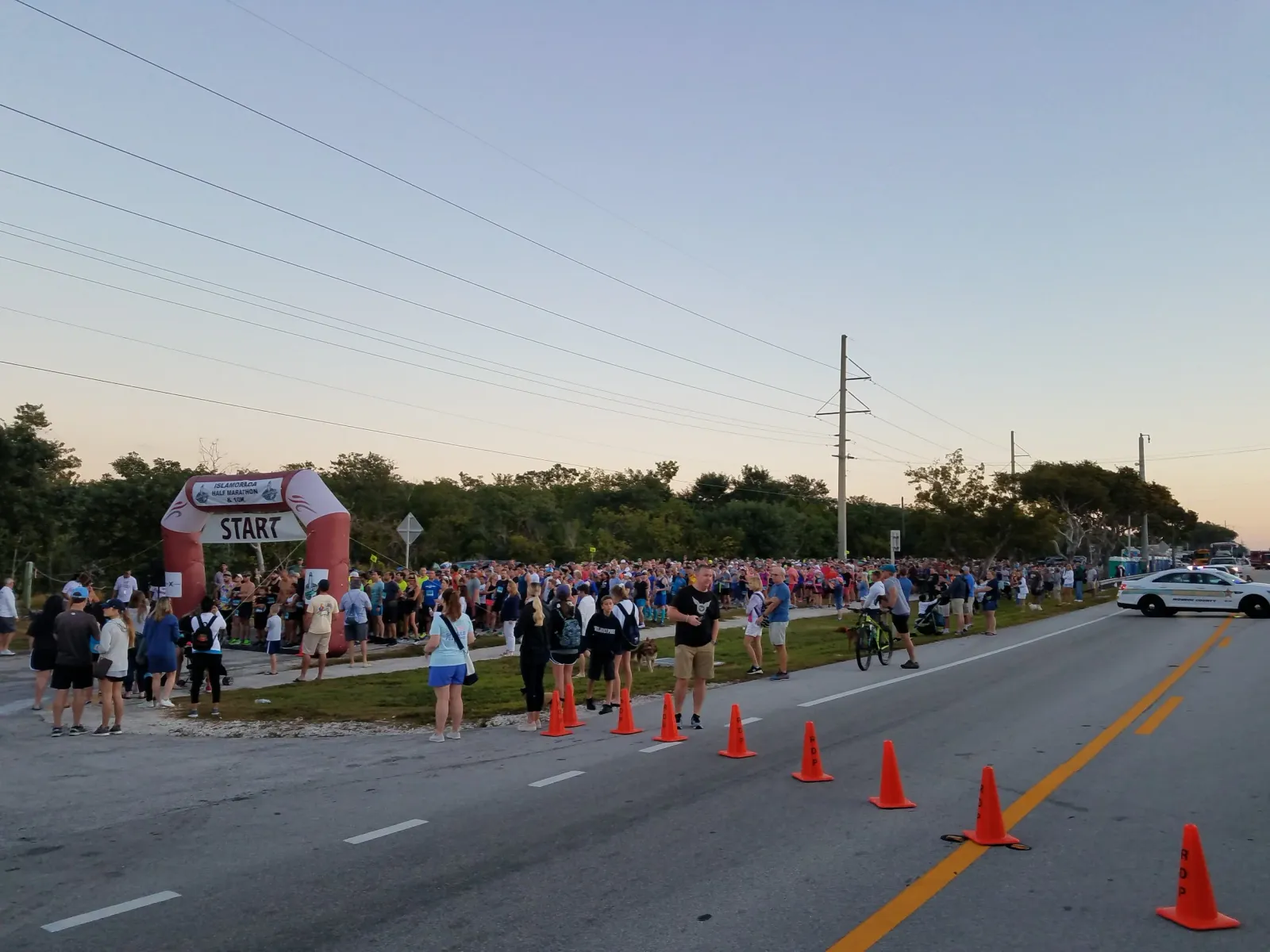 A large crowd of runners gathered at the start line of a race, with an inflatable archway overhead.