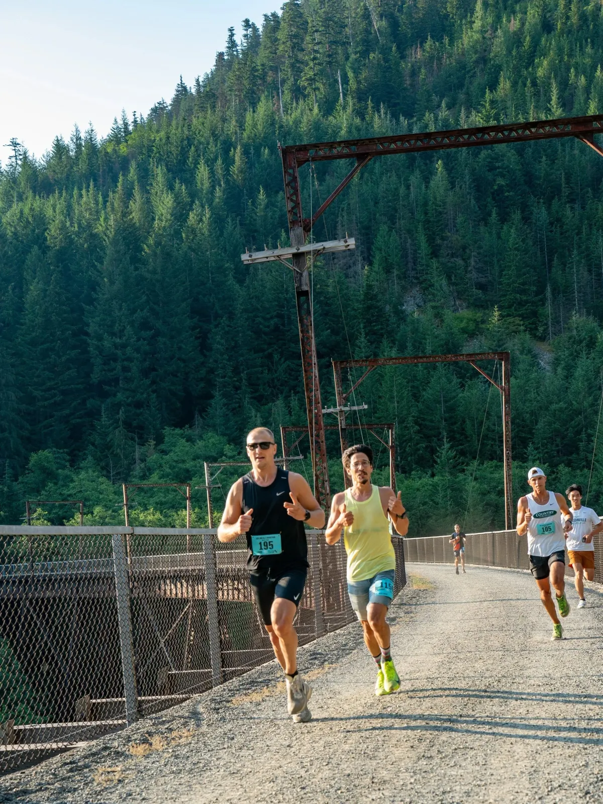Runners on a bridge with a forest in the background.