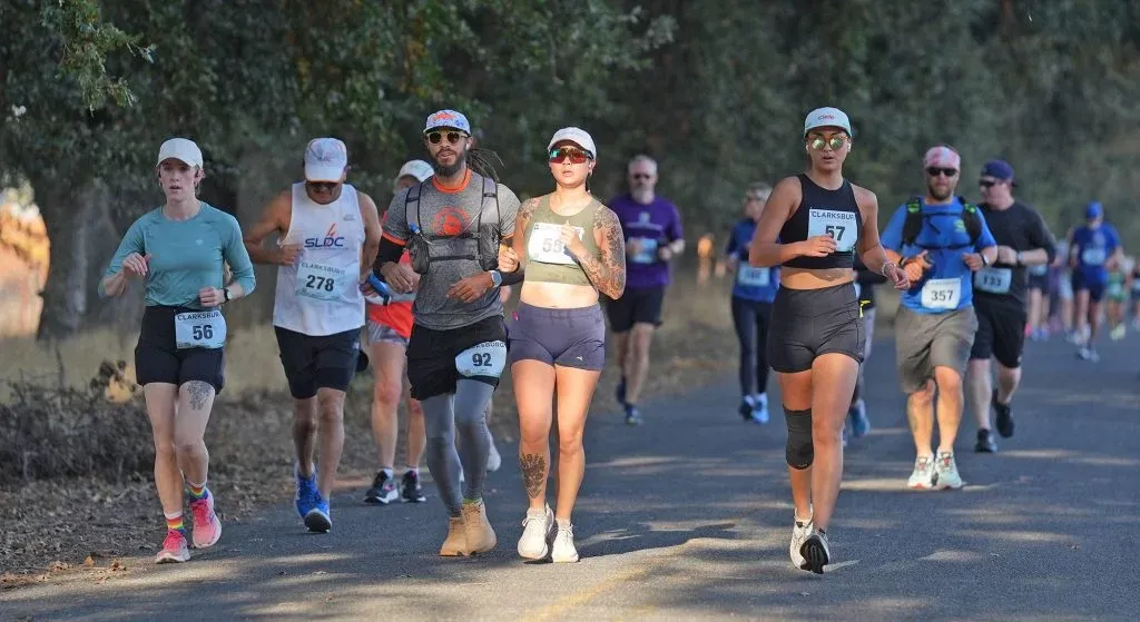 Runners on a paved road during a race, with trees lining the side.