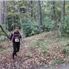A solo runner on a wooded trail during a race.