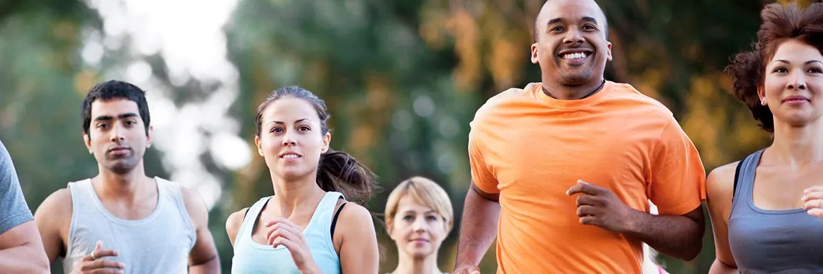A diverse group of people running, smiling and looking engaged.