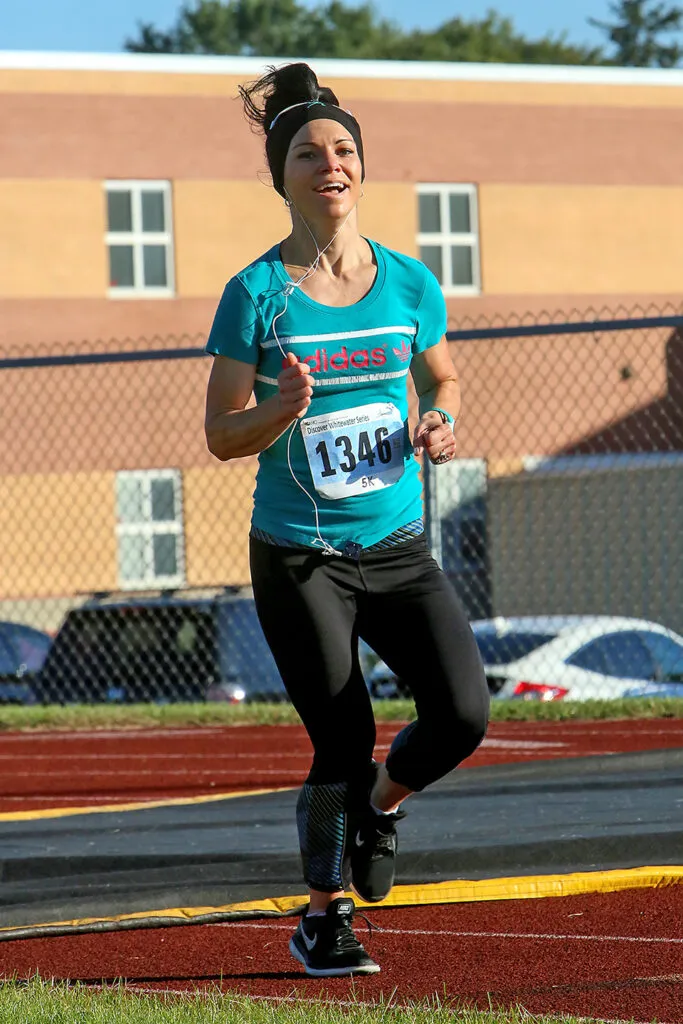 A female runner with a bib number 1346 runs on a track during the Discover Whitewater Series 5K.