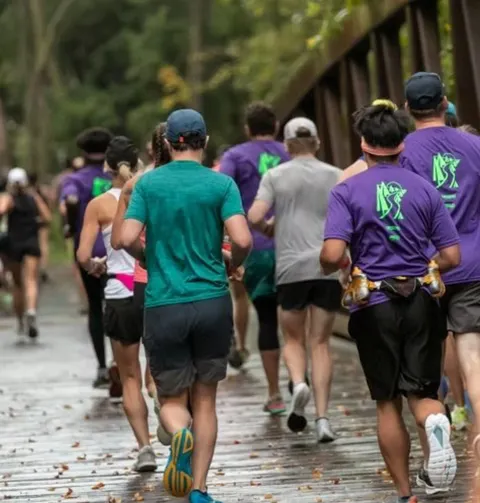 Runners on a wooden bridge during a race, with trees in the background.