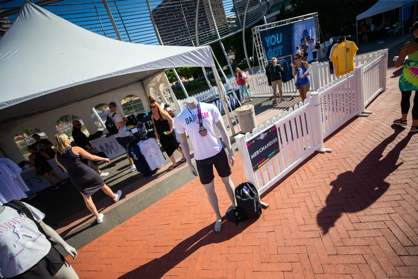 Merchandise tent at a race with people browsing and a mannequin wearing a race t-shirt and medal.