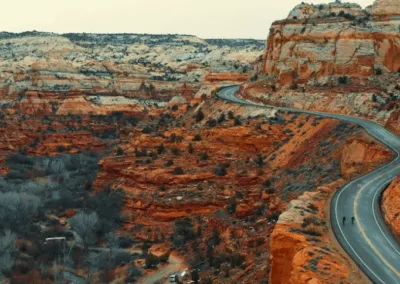 A winding road through a scenic canyon with a few runners visible.