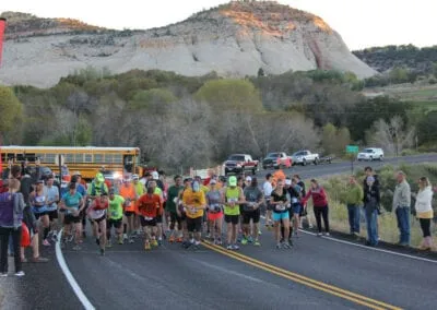 Runners lined up at the start of a race with a large mountain in the background.