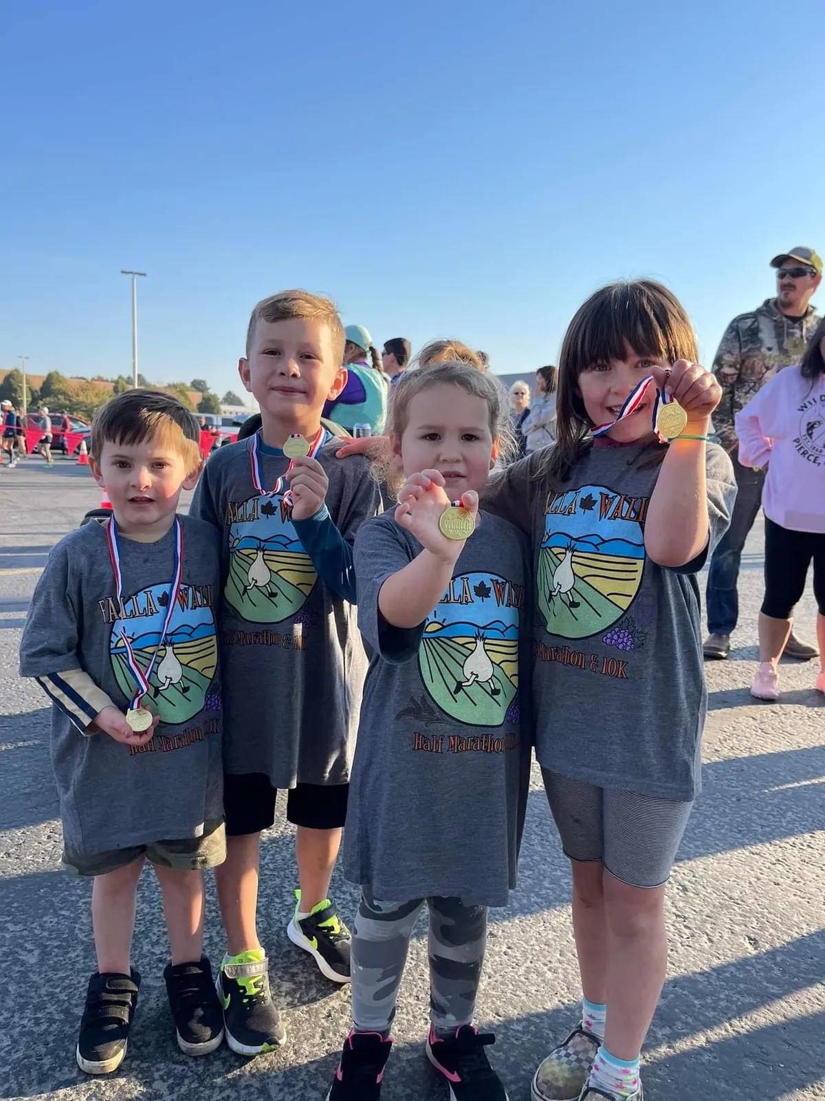 Four children proudly display their race medals after participating in the Falla Walla Half Marathon, 10K, and 5K Run.