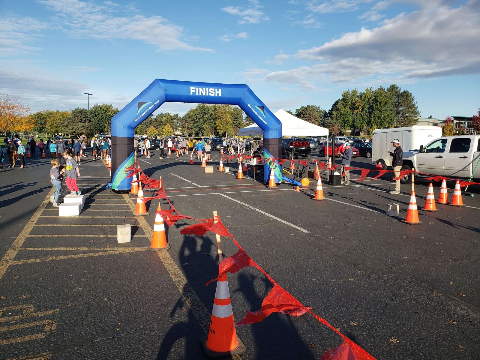 Children on a podium at the finish line of a race, with an inflatable arch and crowd in the background.