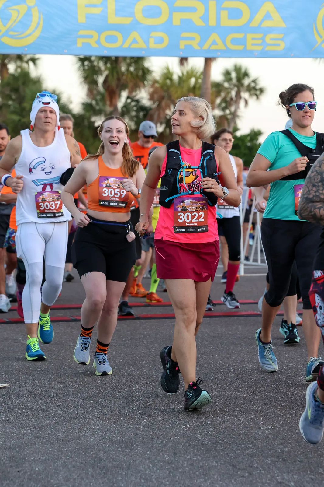 Runners starting a race under a Florida Road Races banner, with one runner in a Stay Puft Marshmallow Man costume.