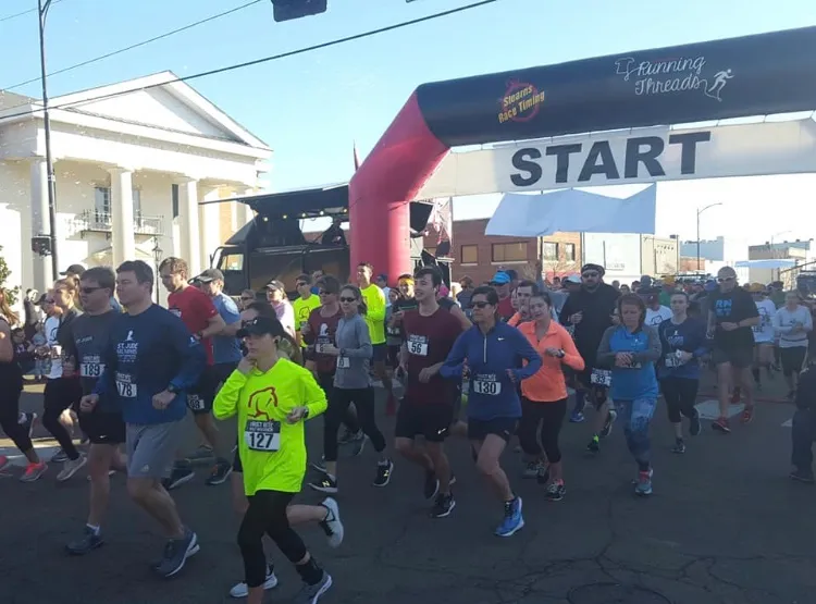 Runners starting a race under a large inflatable arch with 'START' written on it.