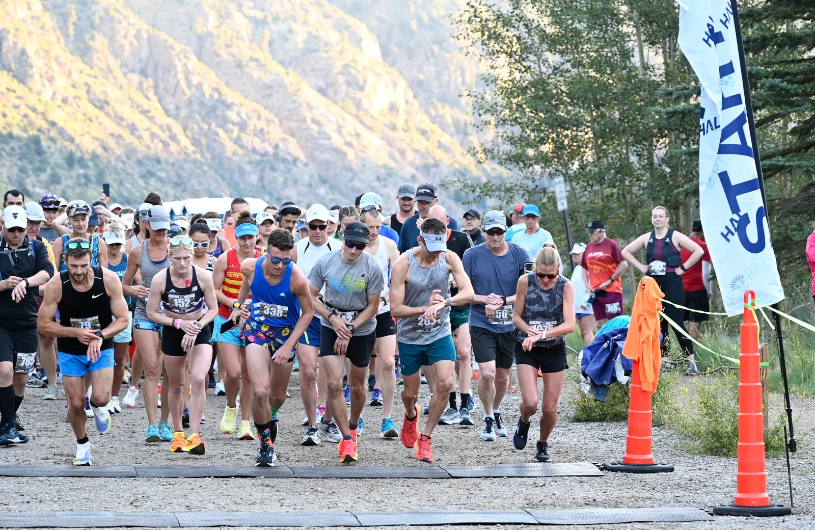 Runners at the starting line of a race with mountains in the background.