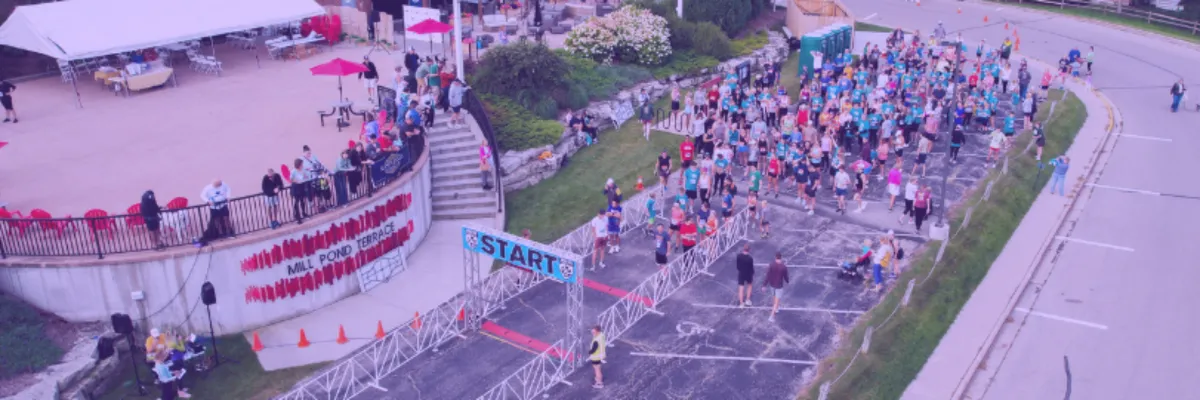 A large crowd of runners gathered at the start line of a race, with a banner overhead that reads 'START'.