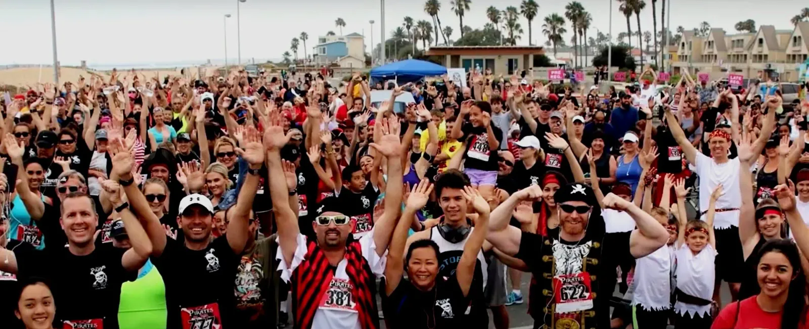 A large group of runners with their hands raised in excitement at a race event.