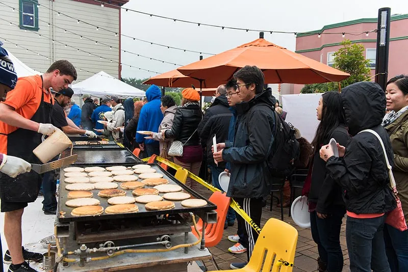 People lining up for a pancake breakfast at an outdoor event.