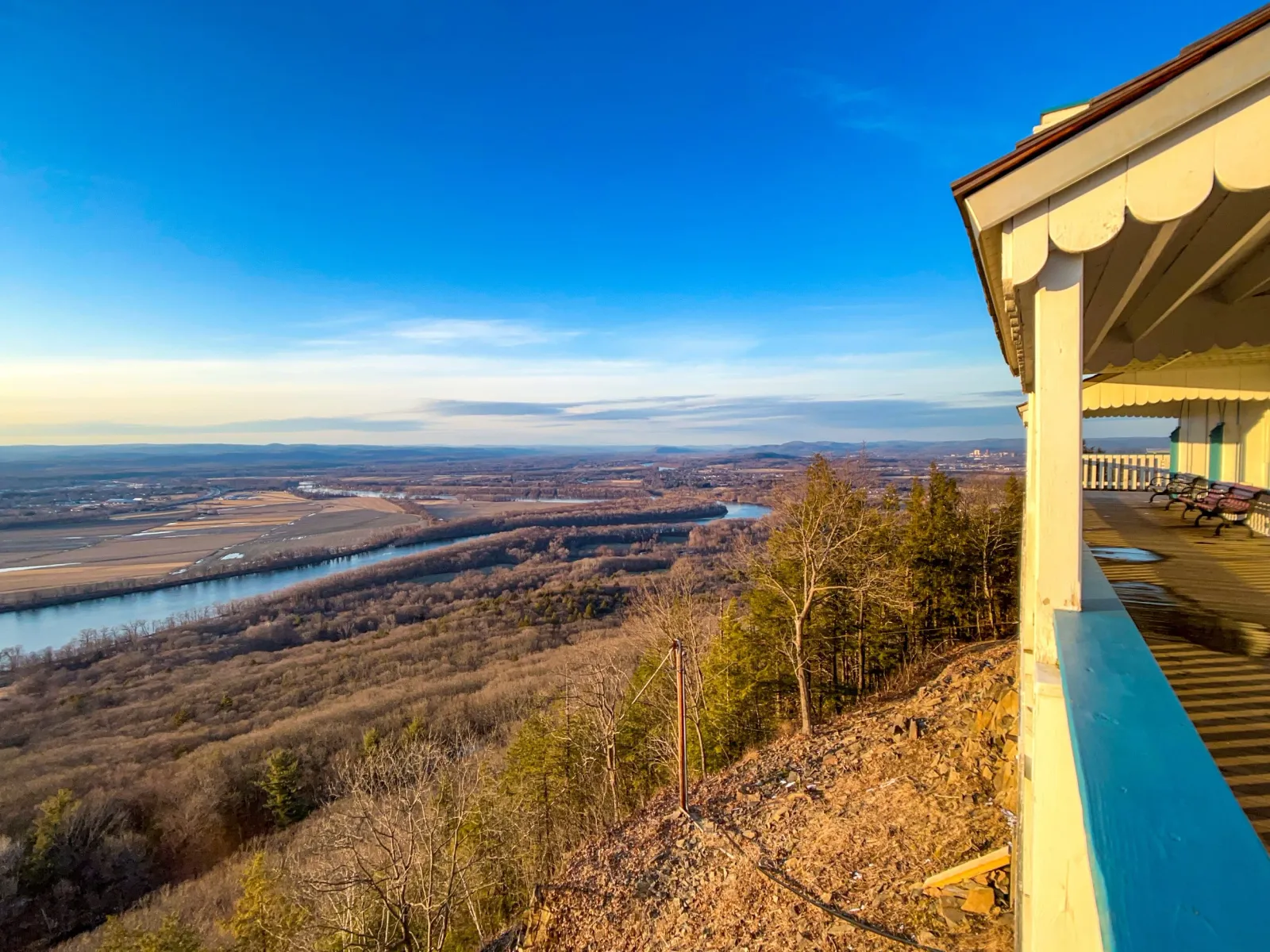 Scenic view of a river valley with a town in the distance, seen from a high vantage point with a building in the foreground.