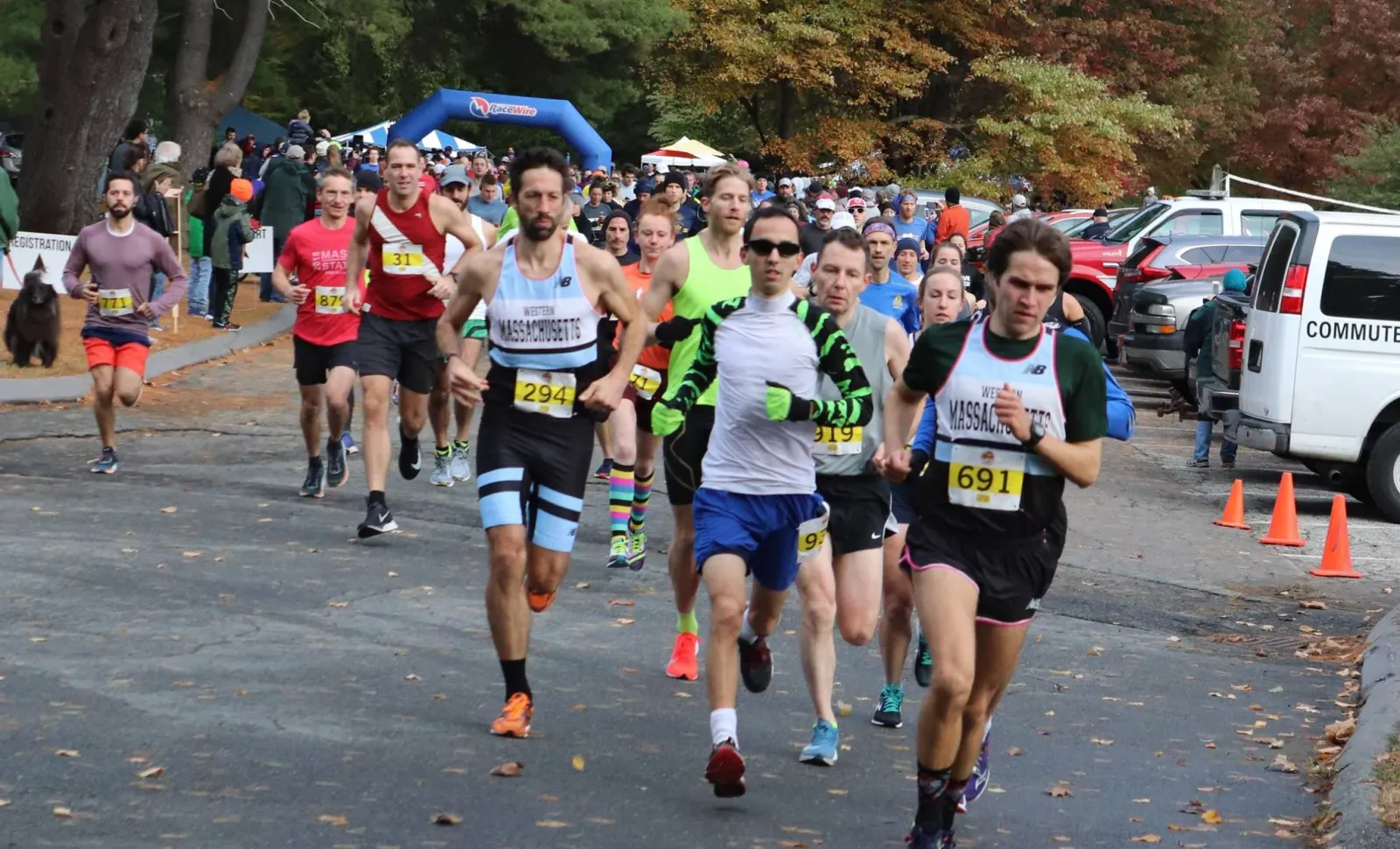 Runners in racing bibs start a road race, with an inflatable arch in the background.