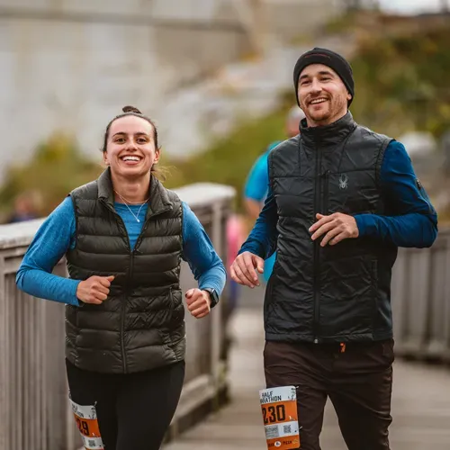 A man and a woman running a race, both smiling.