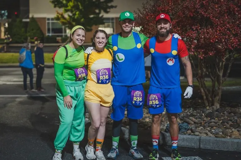 Four runners in Mario and Luigi costumes pose for a photo at a race.
