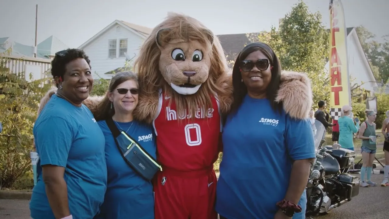Three women and a lion mascot posing for a photo at a race event, with a 'START' banner visible in the background.