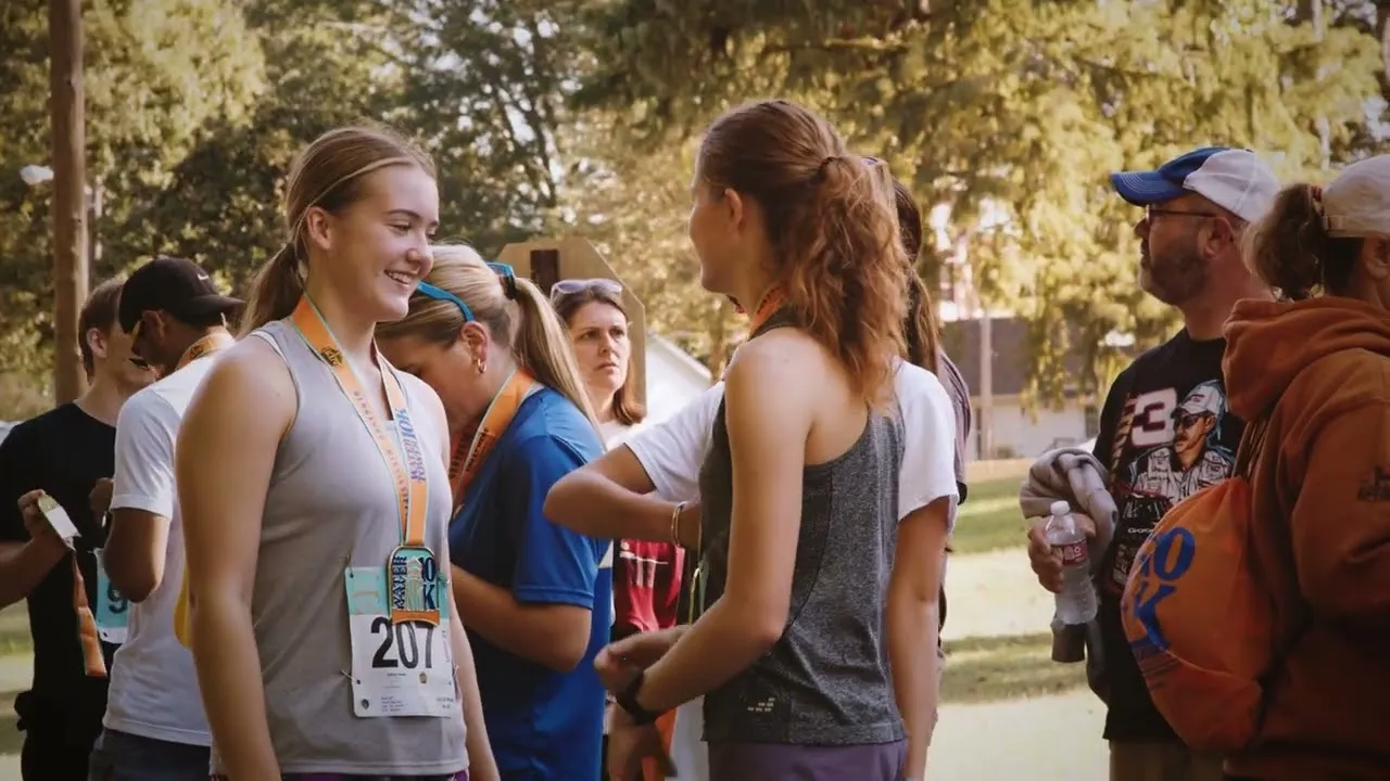 Runners smiling and receiving medals after a race.