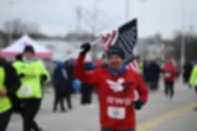 Runner holding an American flag while running in a race.