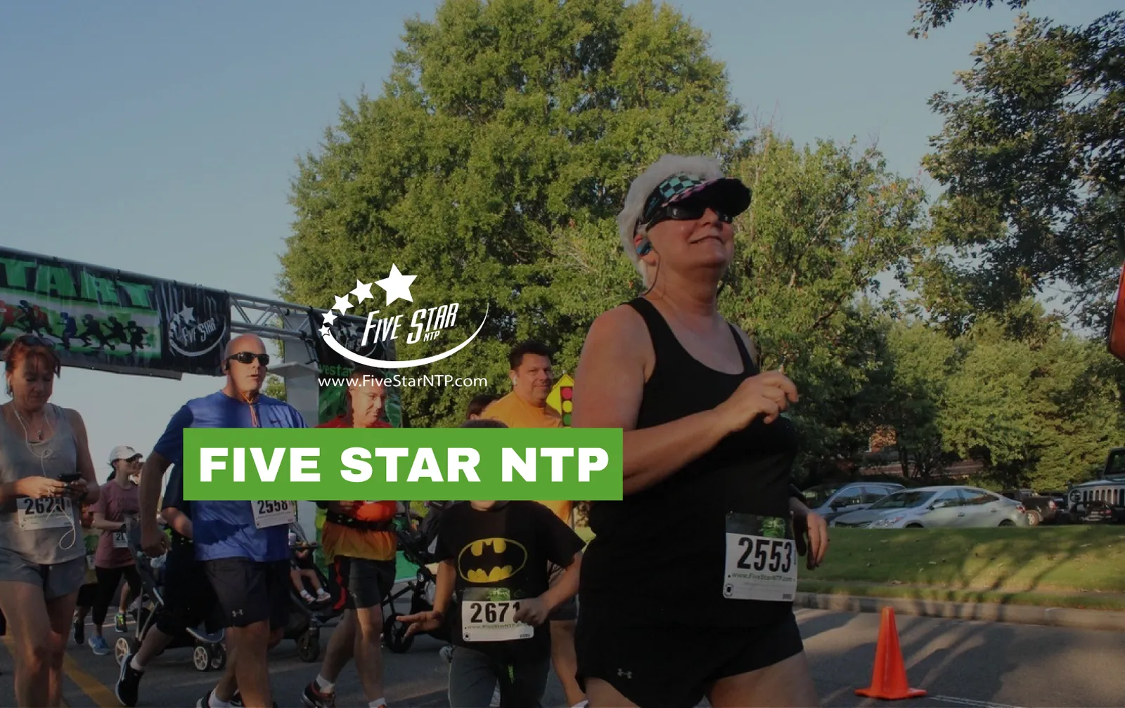 Runners crossing the start line at a race, with a large green banner displaying 'FIVE STAR NTP'.