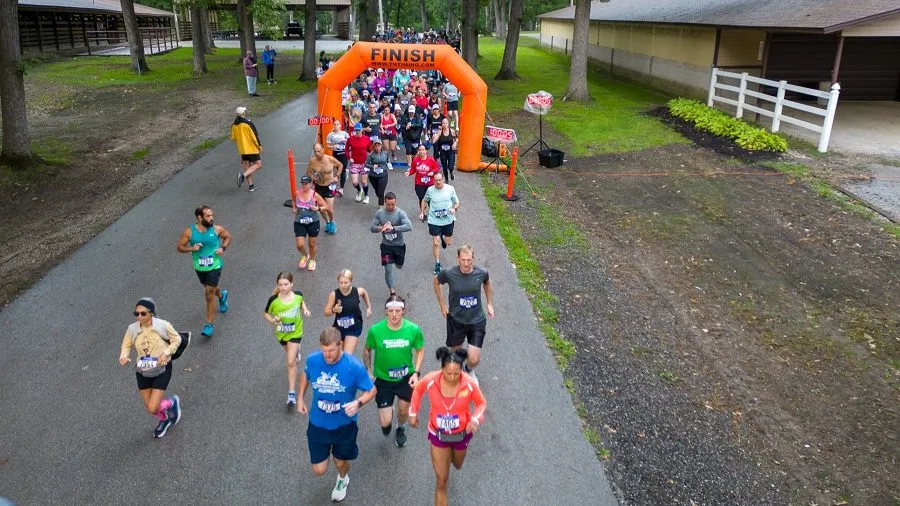 Runners starting a race, with an orange inflatable archway labeled 'FINISH' overhead.
