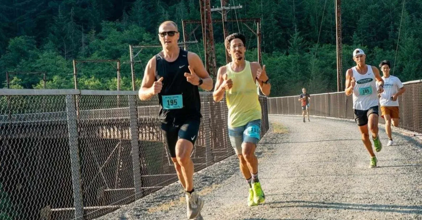 Runners on a bridge during a race, with trees in the background.