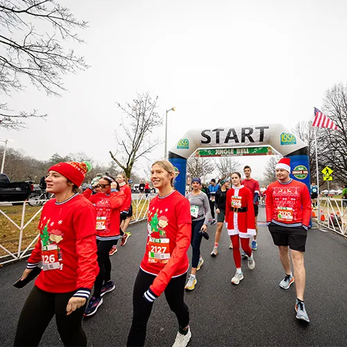 Runners in festive holiday attire gather at the start line of the Jingle Bell Half Marathon & 5K.