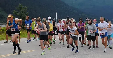 Runners starting a race on a road with mountains in the background.
